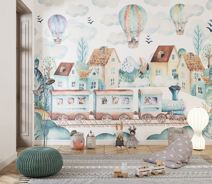 Watercolor illustration features a picturesque village with charming houses and lush trees, set against a backdrop of snowy mountains. A whimsical train with animal passengers rolls along the tracks, while colorful hot air balloons float serenely in the sky. The scene radiates a dreamy, adventurous atmosphere filled with soft pastel tones.