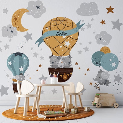 This whimsical illustration features playful koalas in hot air balloons amidst a dreamy night sky filled with stars, clouds, and a crescent moon. The central balloon bears the name "Selim" on a ribbon, adding a personal touch to the enchanting scene. Perfect for a nursery or children's decor.